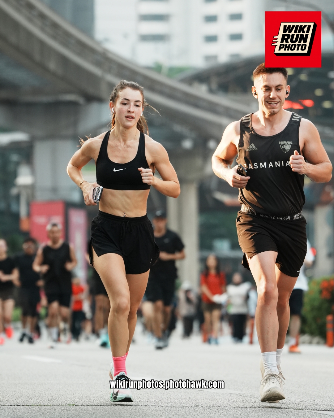 Two runners sharing a stride on a city street.